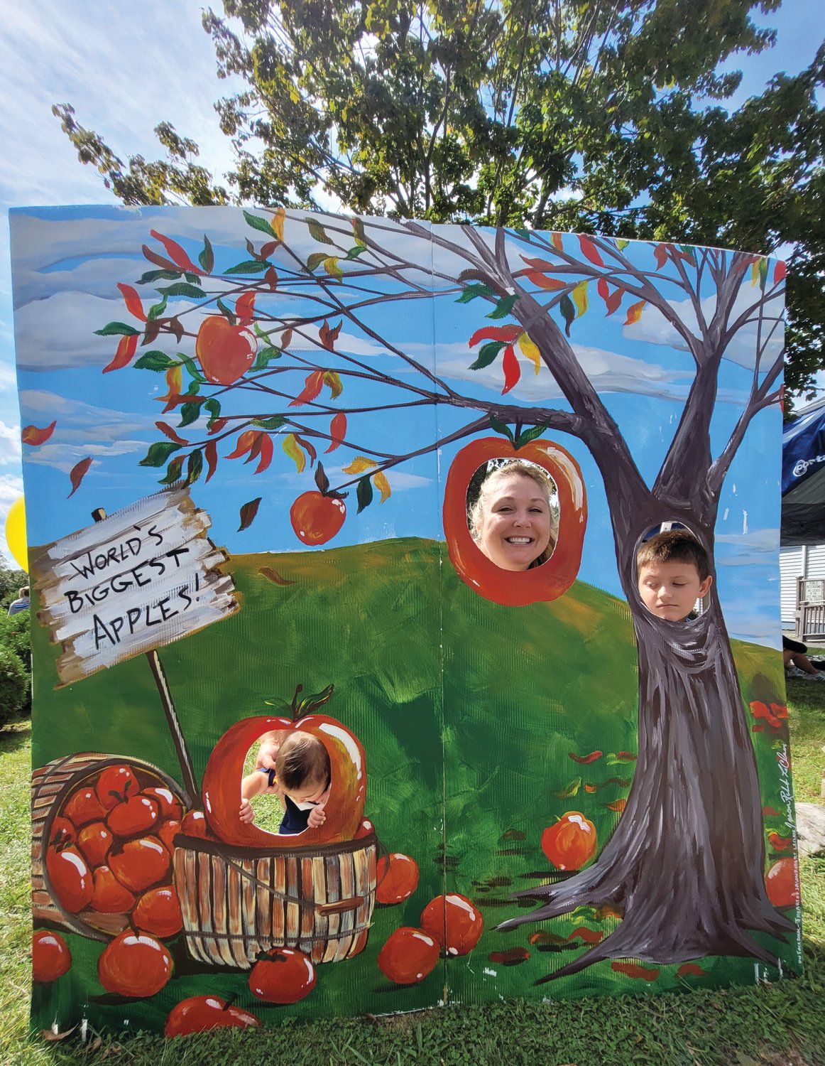 APPLE HEADS: Boston Wood refused to poke his head out the apple basket, while Katelin and Lincoln Fasciano posed for a photo while poking their heads through a cutout for photos at the Apple Festival last Saturday.